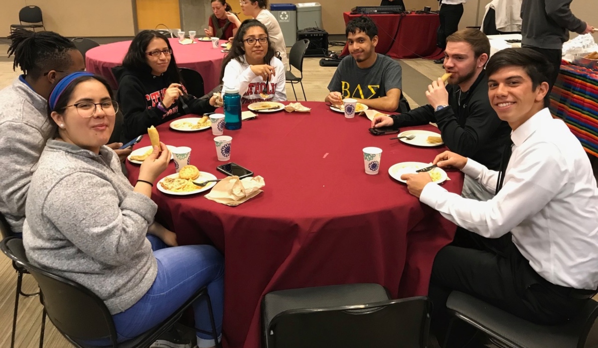 Students sitting at table, eating, and smiling